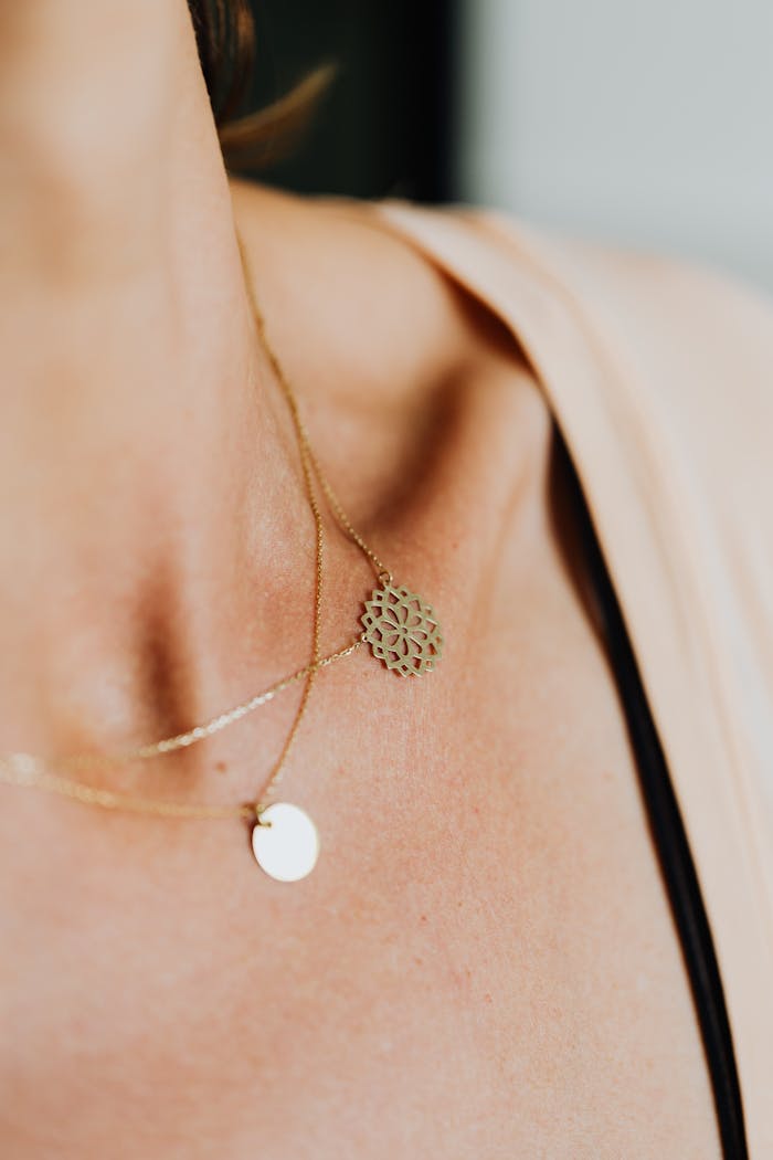 Close-up of elegant gold necklaces adorning a woman's collarbone, showcasing refined jewelry design.